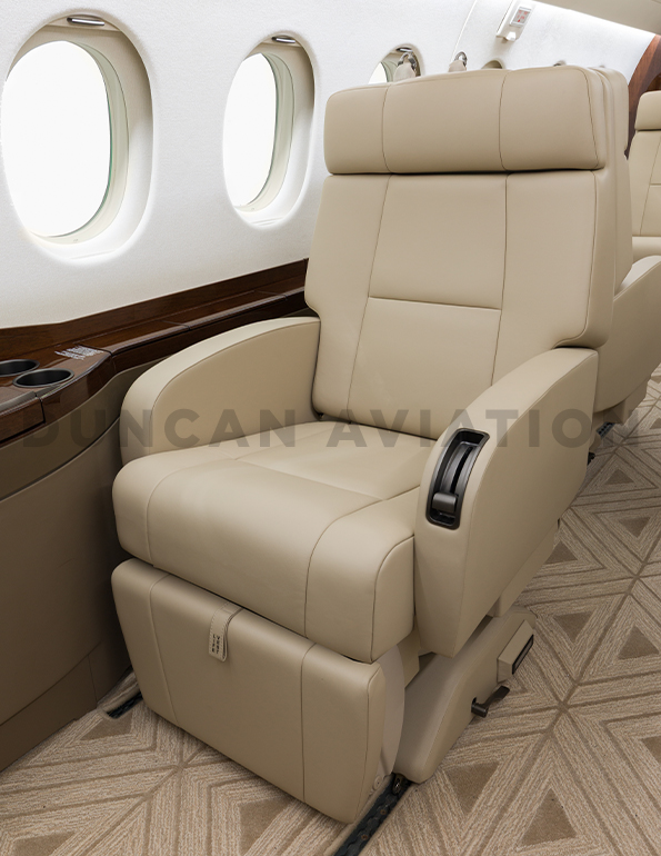 Close up of tan leather captain chair next to drink rail in Falcon 2000 refurbished by Duncan Aviation