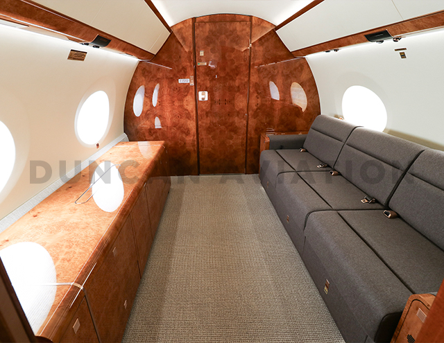 Interior of Gulfstream 650 with cool brown divan couch by Duncan Aviation