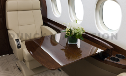 Close up of dark wood pull out table in front of tan leather seat in Falcon 2000 refurbished by Duncan Aviaiton